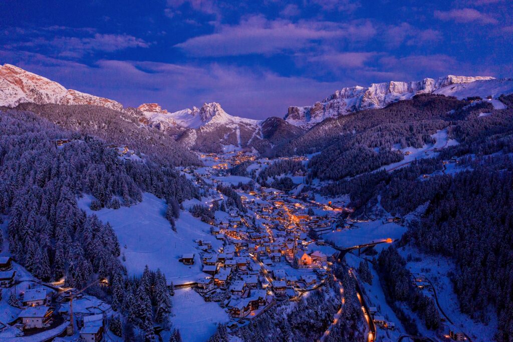 aerial shot of a small bright town between snowy mountains during the evening