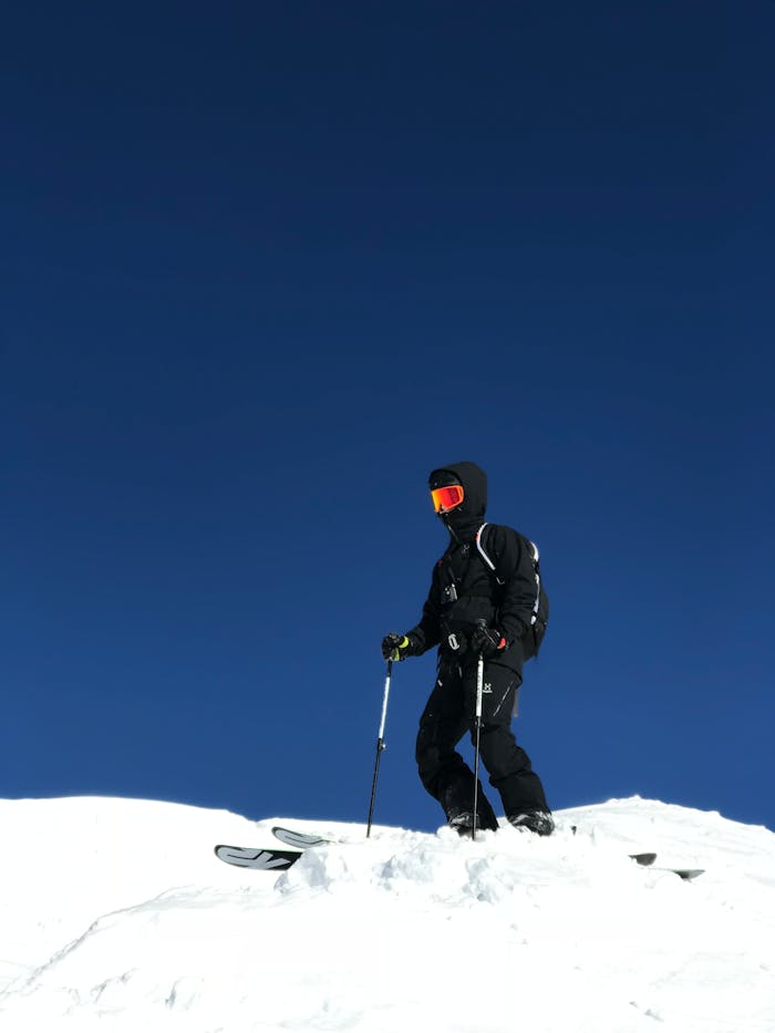 A skier in black gear enjoys a sunny winter day on a snowy mountain slope.