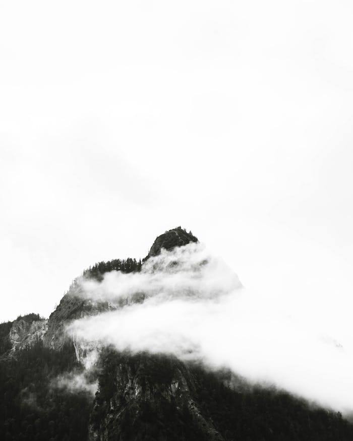 Misty fog envelops a dramatic mountain peak in Schönau am Königssee, Germany.