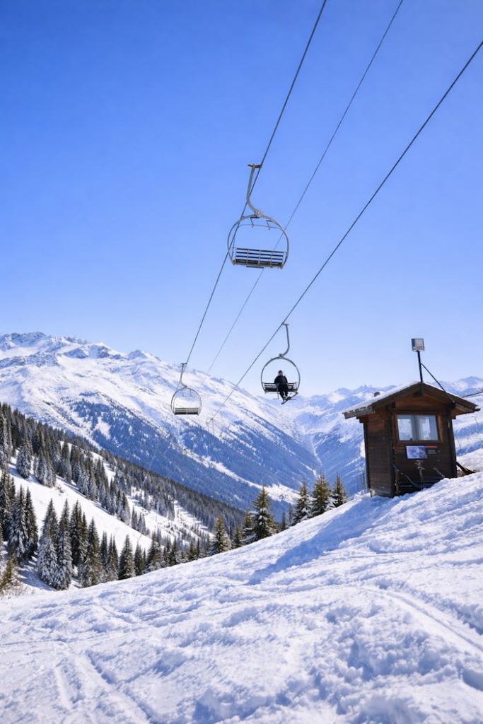 Snowy landscape with ski lift in the French Alps under a bright blue sky.